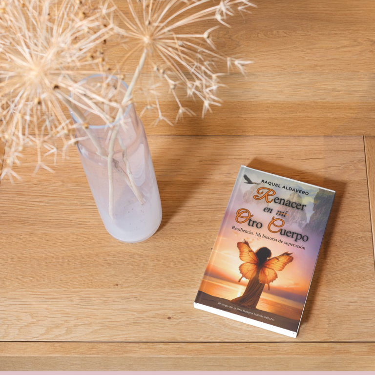 Un libro titulado "Renacer en mi otro cuerpo " junto a una flor seca en un jarrón.